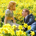 a man and woman sitting in a field of yellow flowers